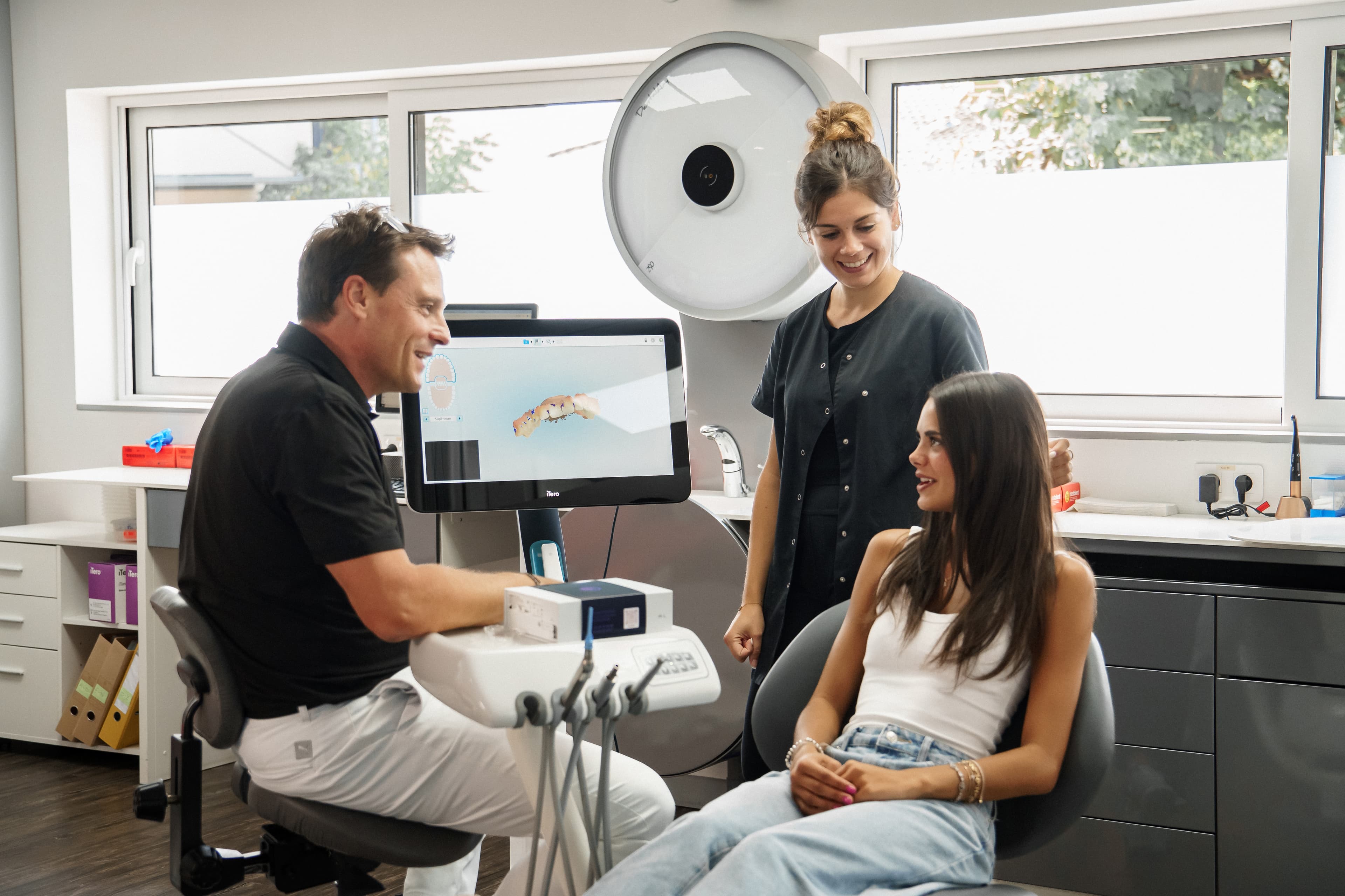 Praticien, assistante et patiente souriants